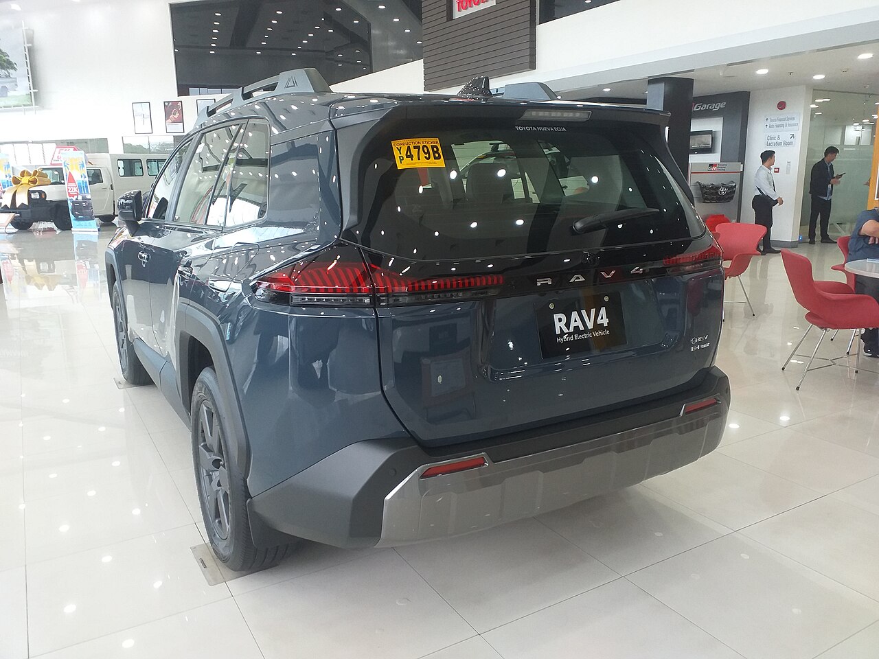 Rear three-quarter view of a blue 2026 Toyota RAV4 Woodland HEV AWD at a Toyota dealership